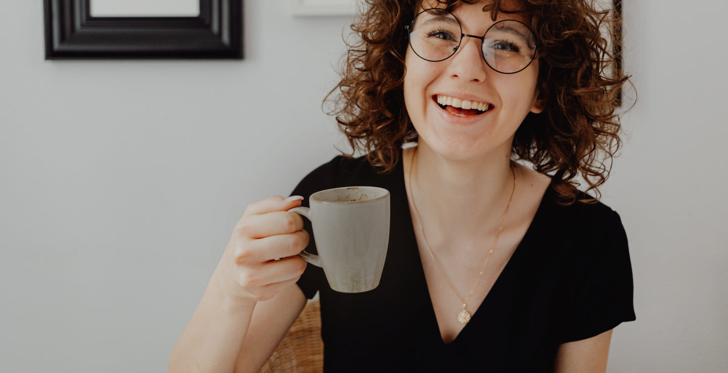 Woman smiling holding grey coffee mug with coffee