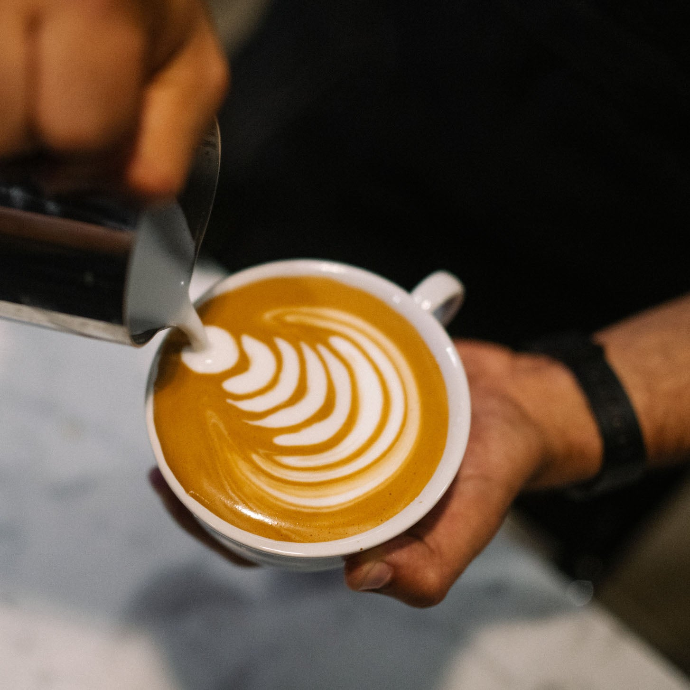 A Peet's barista pouring latte art 