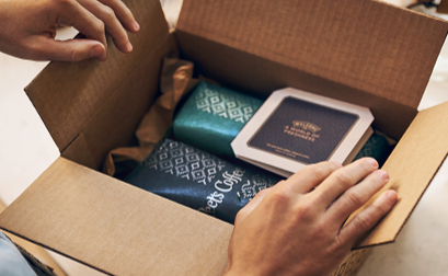 A man opening a box with two bags of coffee inside